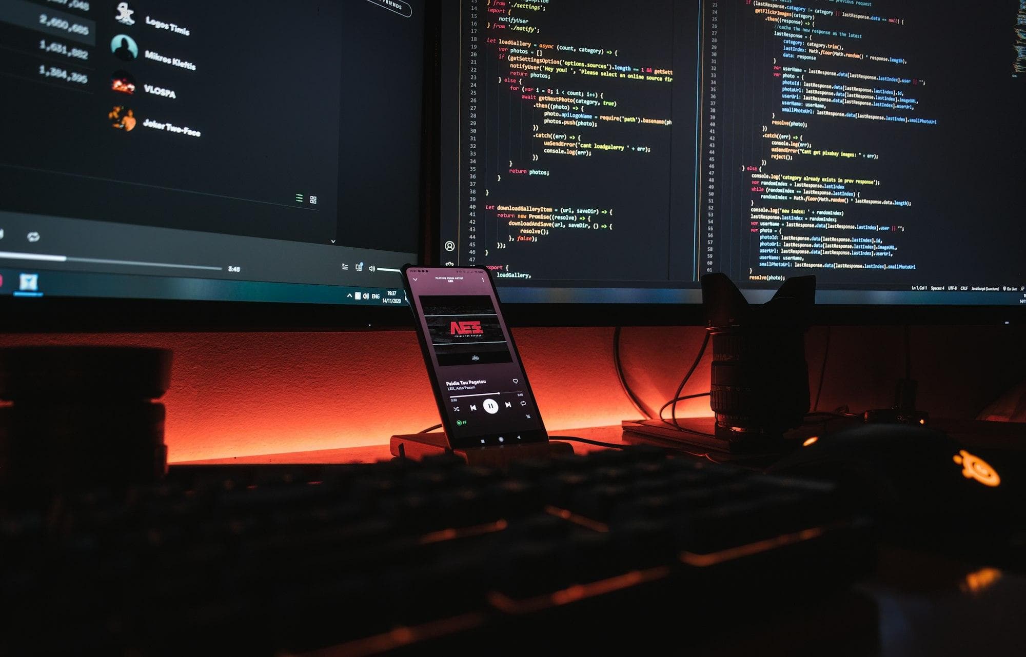 Developer workstation with code on two monitors and a warm orange glow