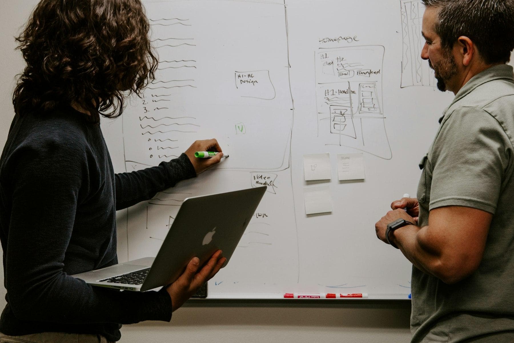 Two engineers sketching a system design on a whiteboard