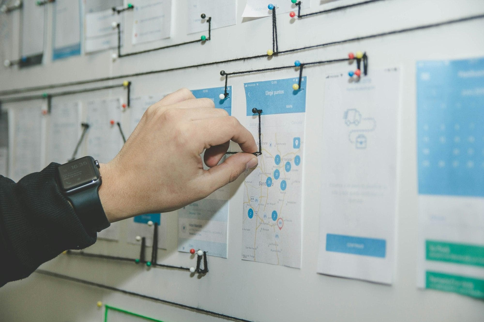 Designer arranging printed wireframes on a wall
